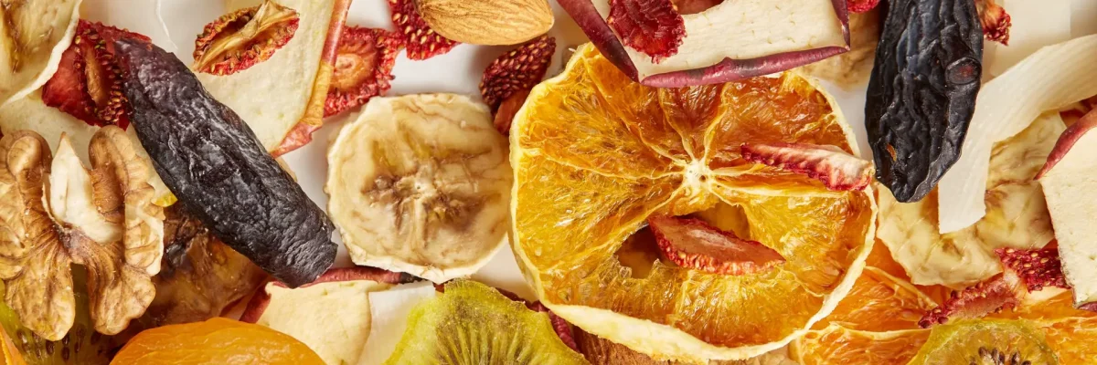 Close up of almonds, dried apricot, raisins, walnuts, dried apples, orange, bananas and kiwi on white background. Concept of organic healthy assorted dried fruit for snacks.
